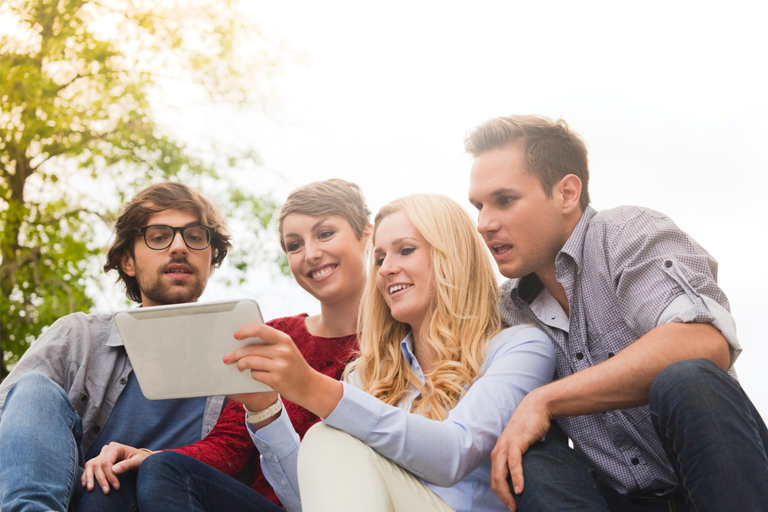 Vier Studenten schauen gemeinsam auf Tablet