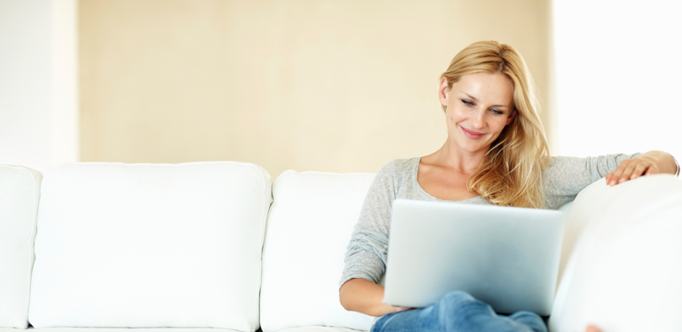 Frau auf Sofa mit Laptop auf dem Schoß